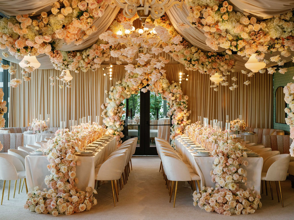 Elegant event space with floral decorations, draped fabric, and long tables set for a celebration.