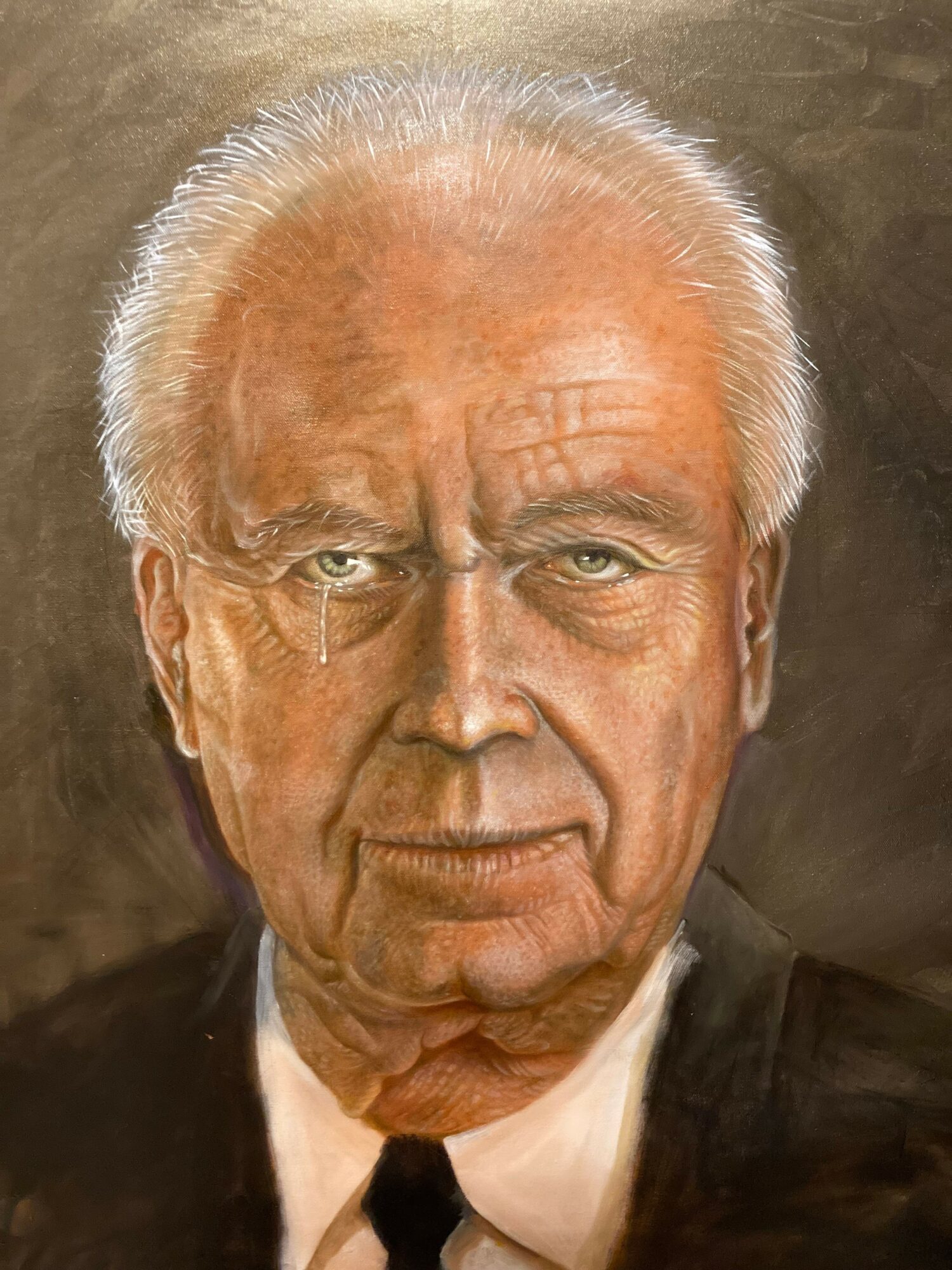 Portrait of an elderly man with white hair, glasses, and a serious expression, wearing a suit and tie.