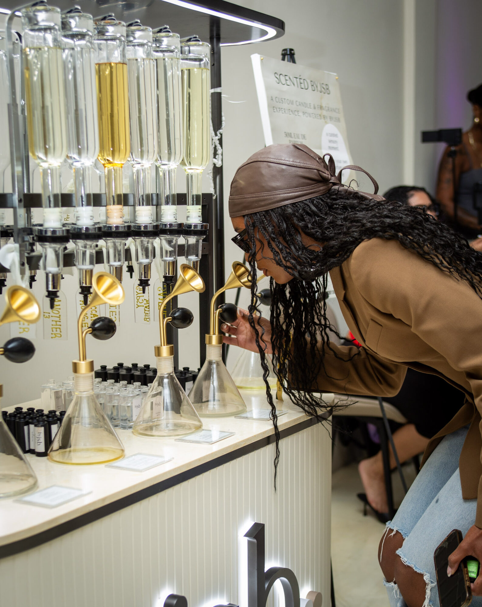 Woman with long curly hair and brown headscarf examines laboratory equipment at a display counter.