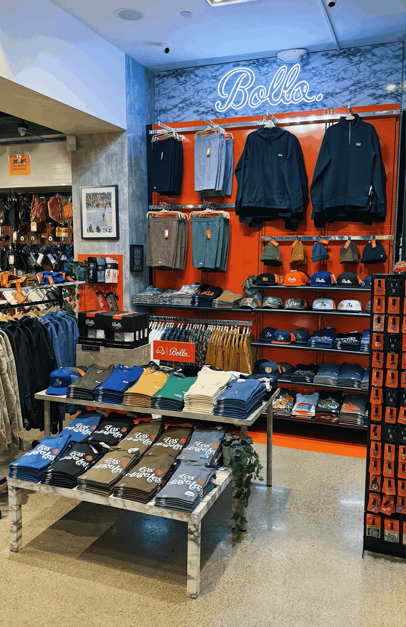 Clothing display with jackets, hats, and folded shirts in a retail store, with a neon sign reading 'Ballin' in the background.