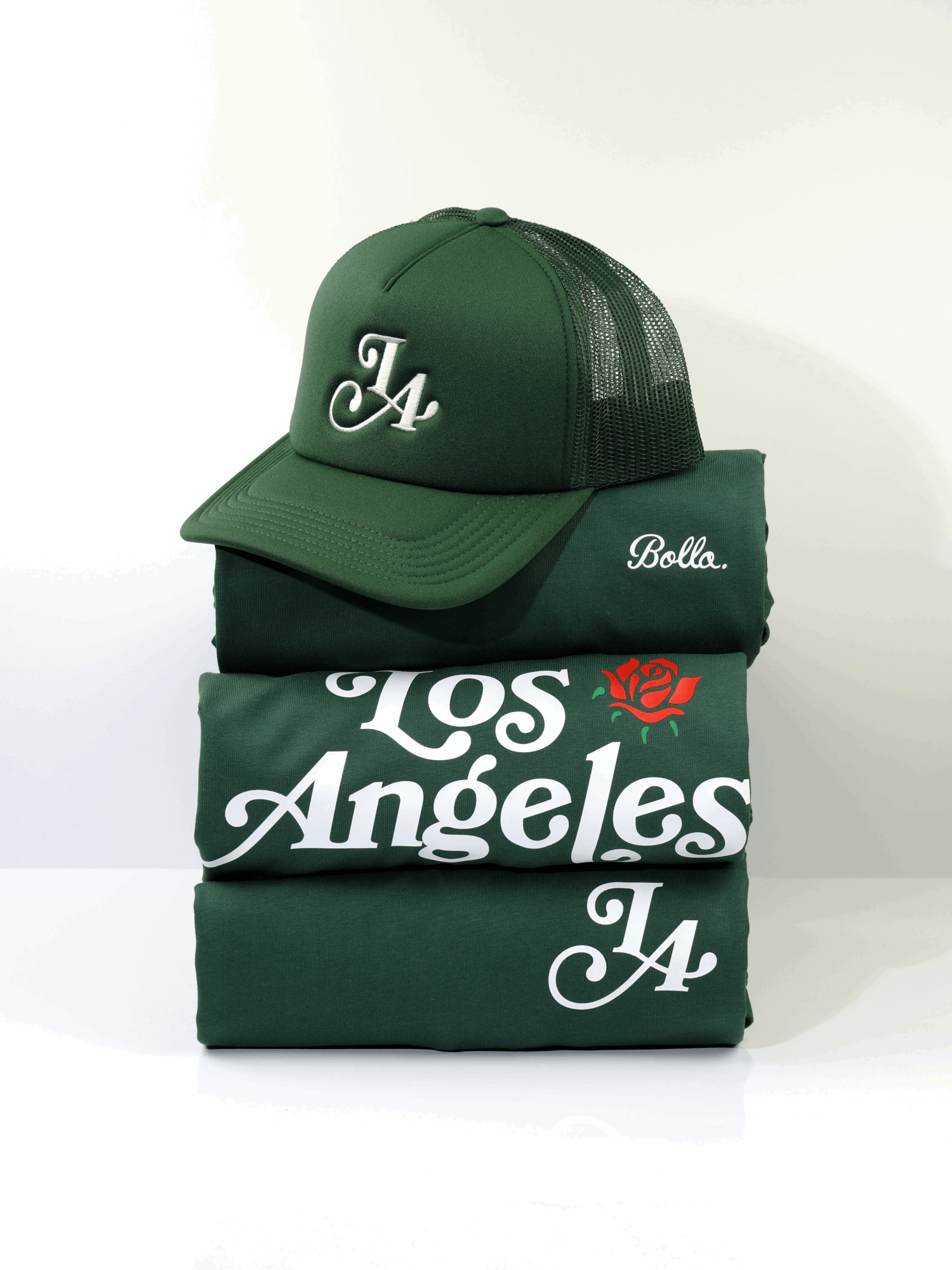 Stack of four green clothing items with a green cap on top, against a white background.
