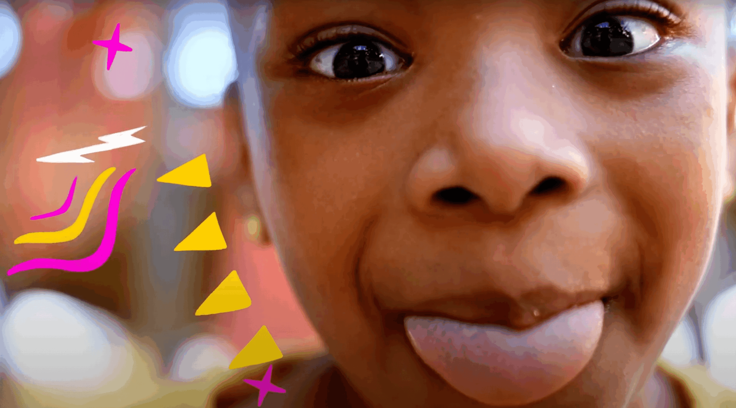 Close-up of a child's face with tongue out, eyes wide open, and playful expression, with colorful doodles on the left side.