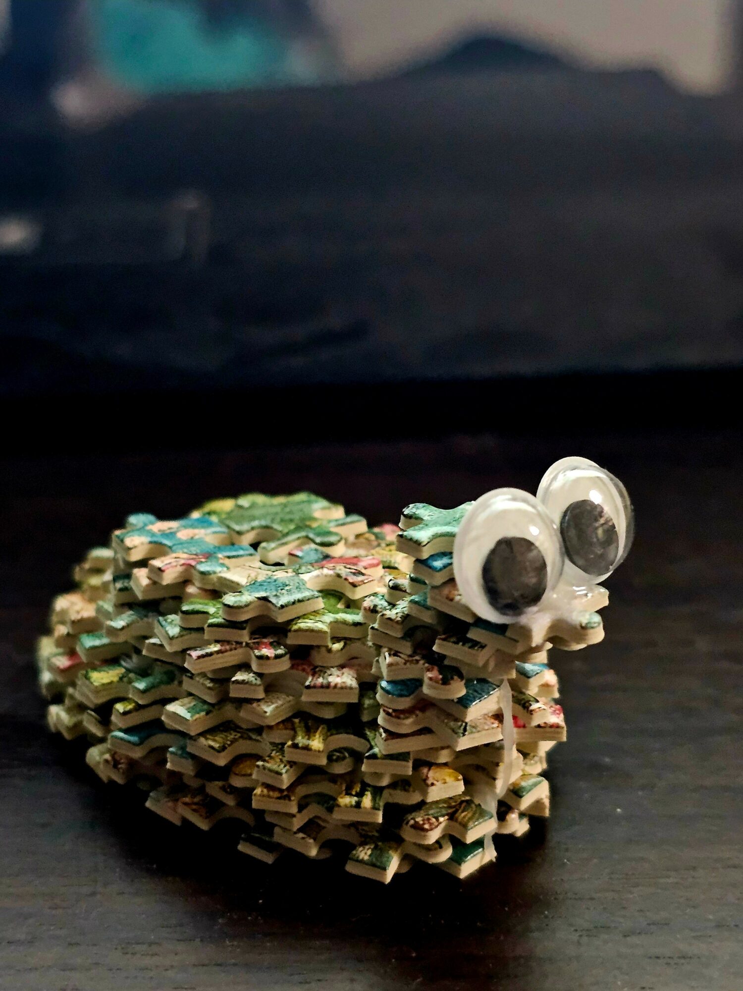 Small craft made of colorful paper strips with googly eyes on a dark surface.