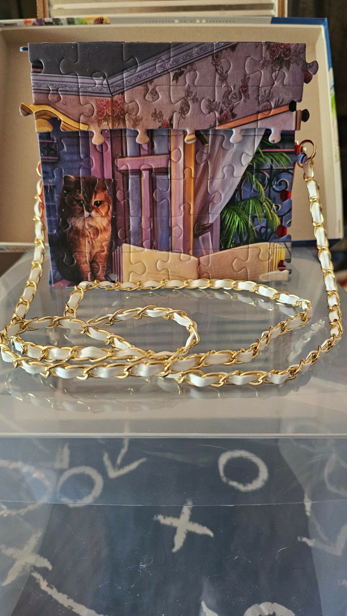 Stack of puzzle pieces with a chain on top, placed on a surface with symbols and shapes.