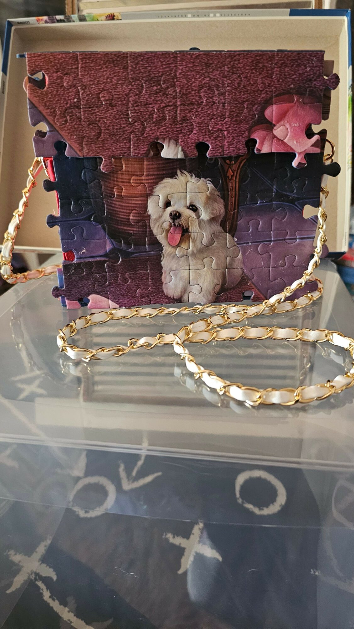 Puzzle piece with a dog and a person, with a heart-shaped decoration above, inside a glass display case.