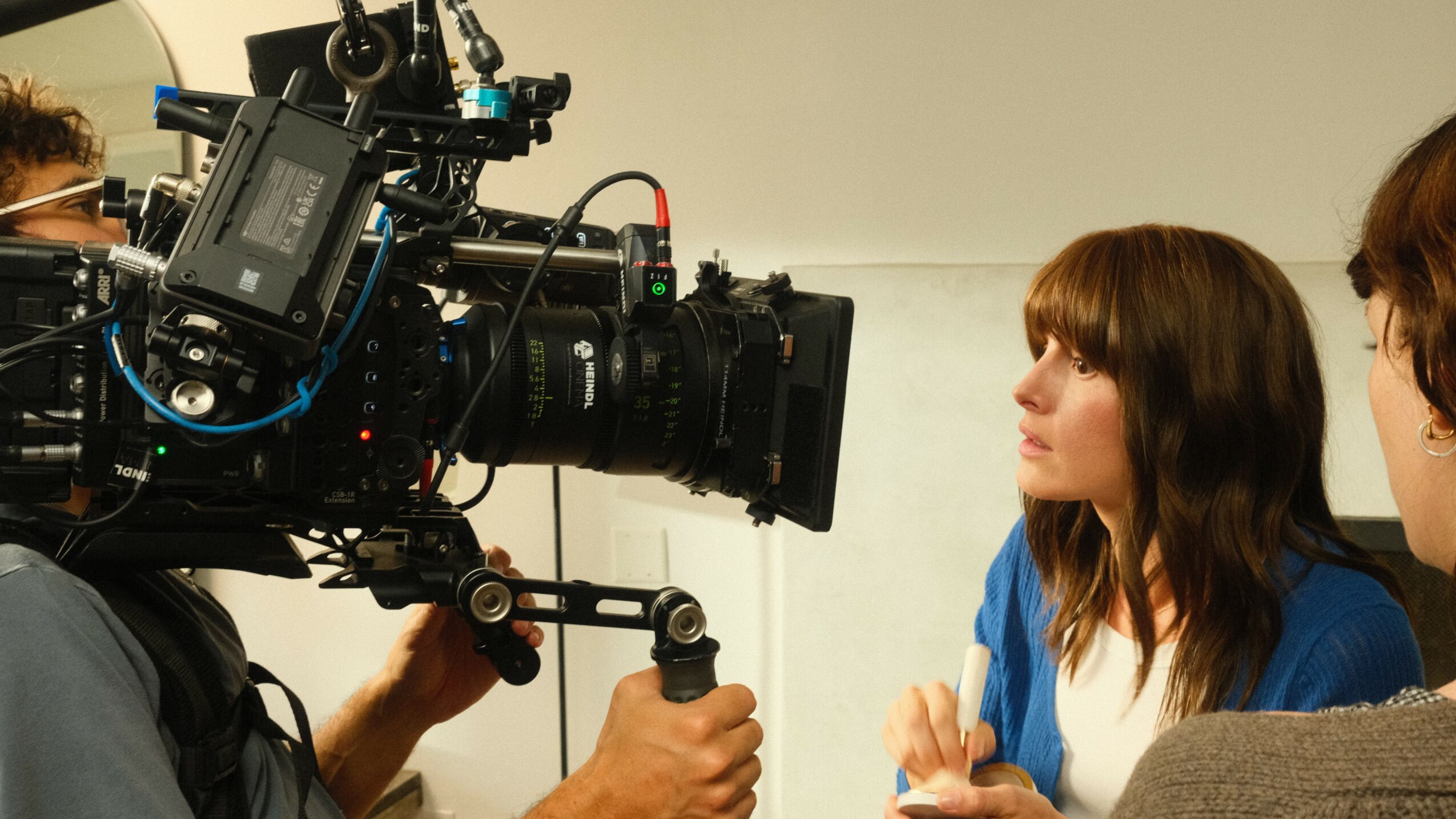 Two women are being filmed with a professional camera in a studio setting.