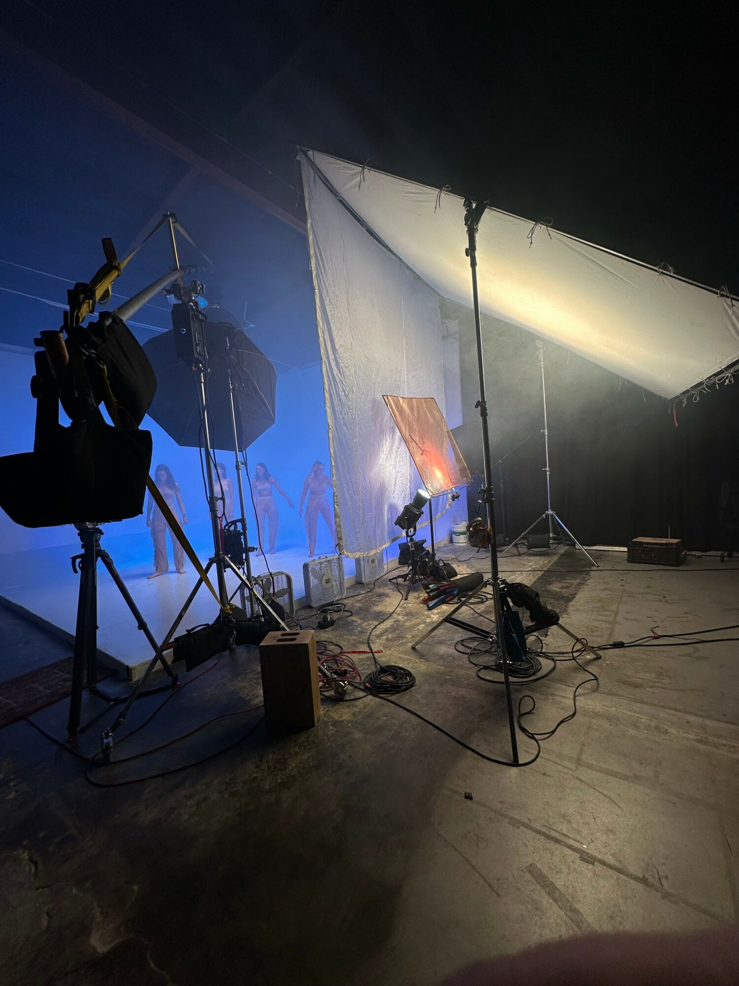 Photography studio with lighting equipment, a backdrop, and a partially visible person, set up on a concrete floor.