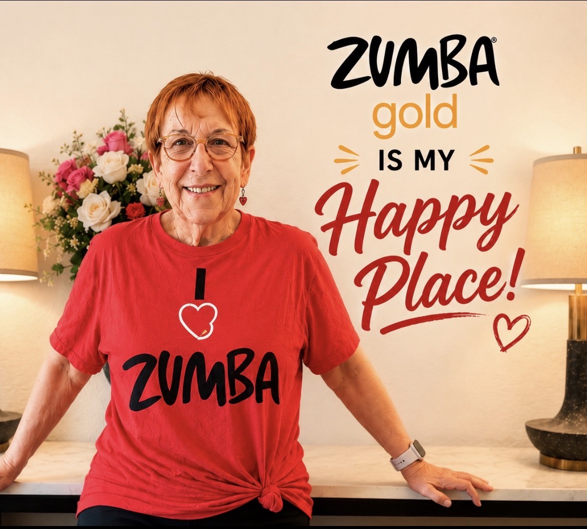 Older woman with glasses and short hair, wearing a red T-shirt, smiling in a room with lamps and flowers, Zumba-themed background.