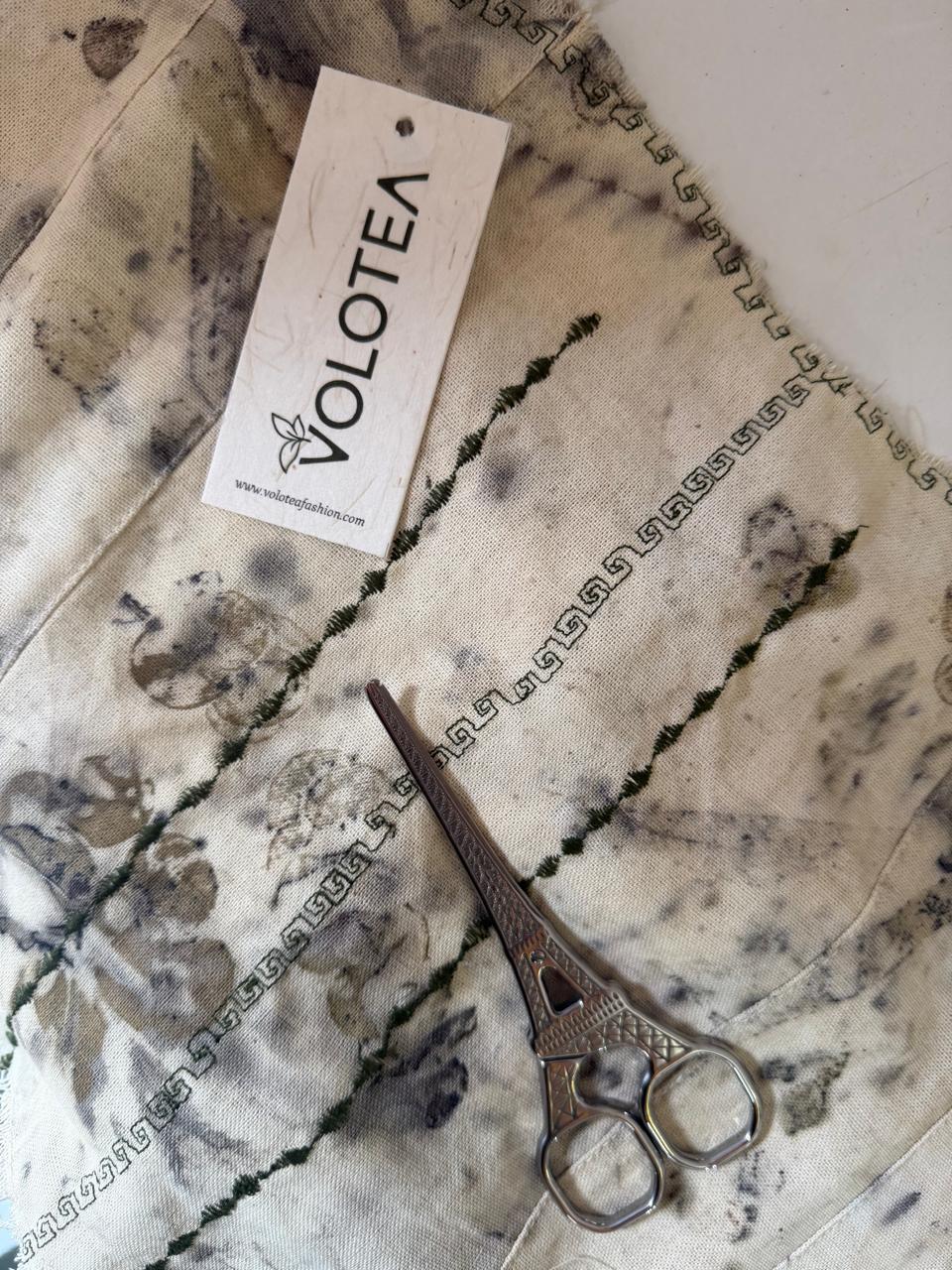 Close-up of marble surface with a pair of scissors and a label reading 'VOLOTEA'.