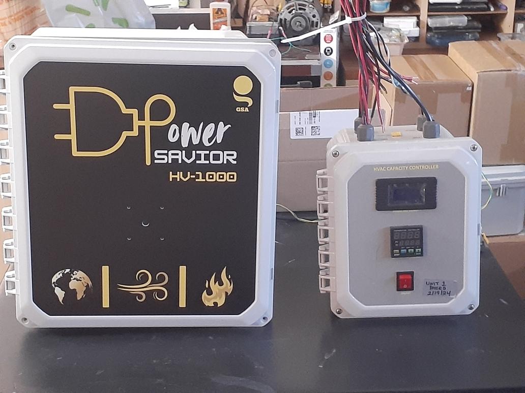 Electrical device with a black and white front panel and a smaller white box with a display and buttons, on a black surface.
