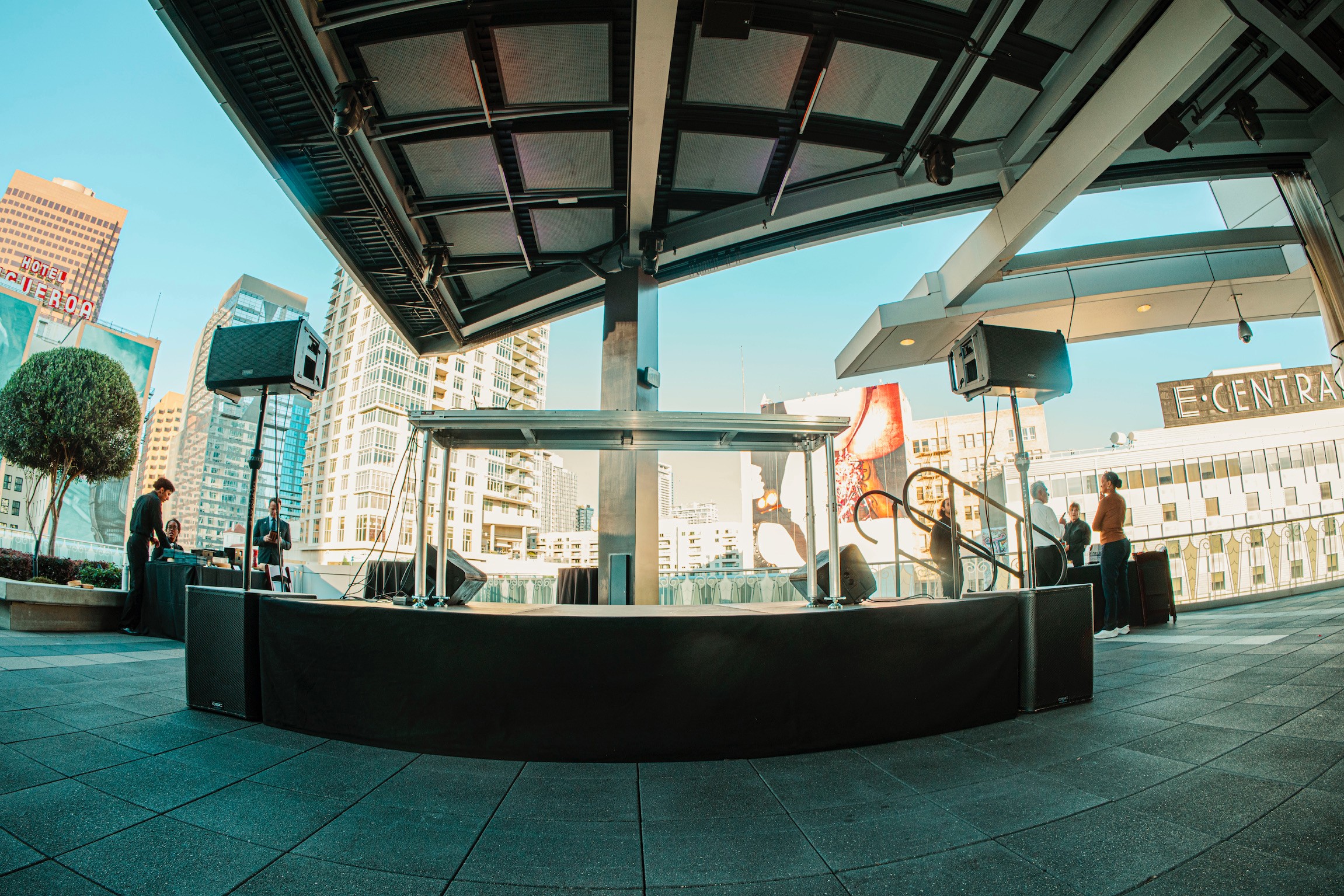 Indoor space with a curved bar, large windows, and city buildings outside, with people sitting and standing.