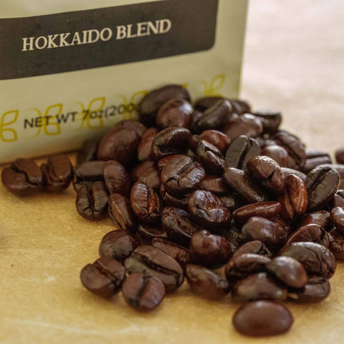 Coffee beans spilled from a bag labeled 'Hokkaido Blend' onto a surface.