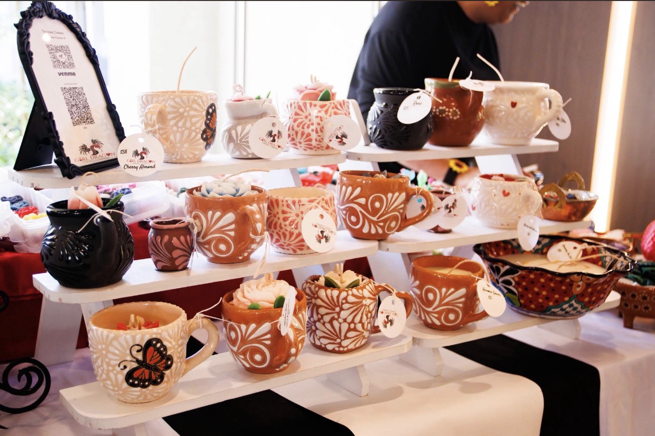 Display of various decorated mugs and teapots on a table with a person in the background, indoors.