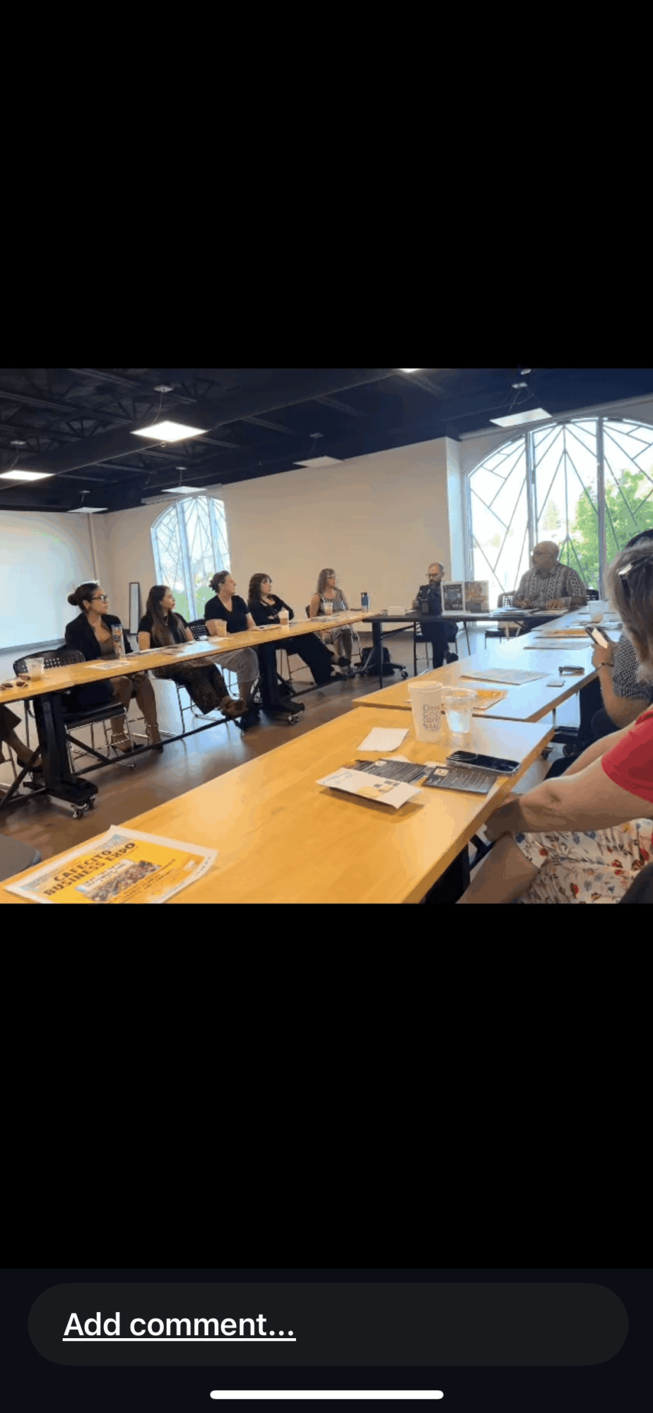 People seated around a conference table in a room with large windows and natural light.