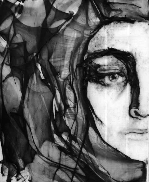 Black and white portrait of a woman with dark, wavy hair partially covering her face, one eye visible.
