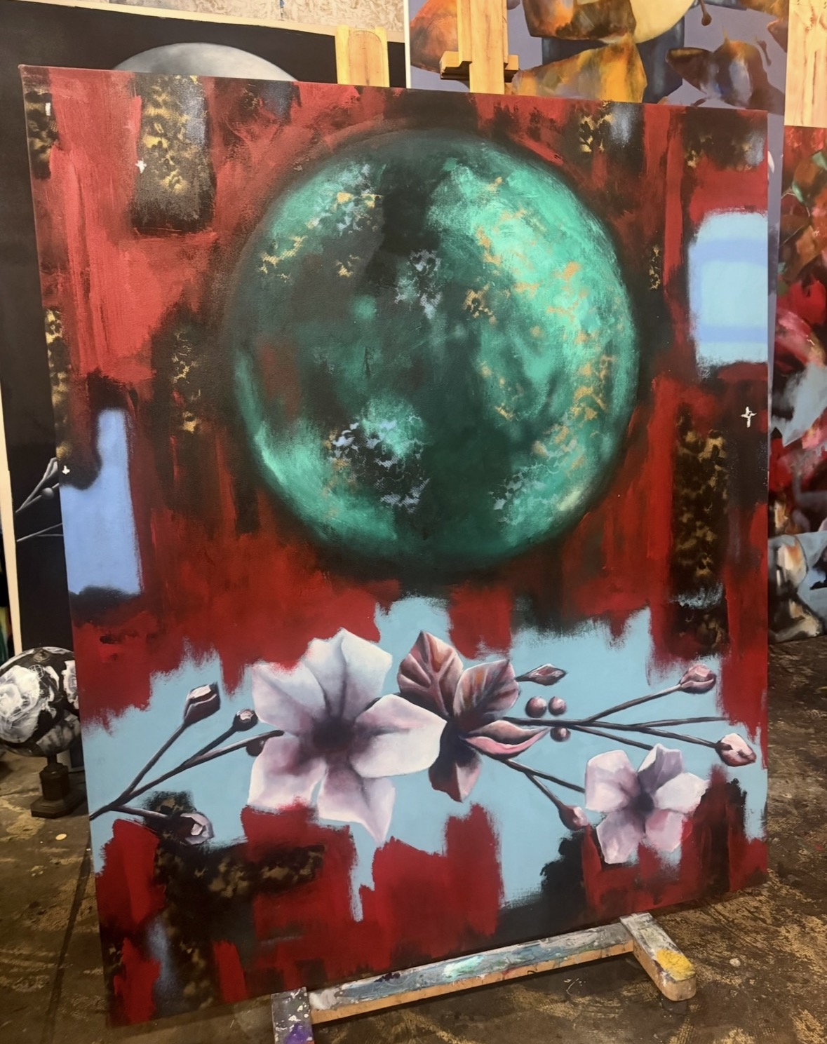 A painting features a large greenish-blue sphere above pink flowers with a red background.