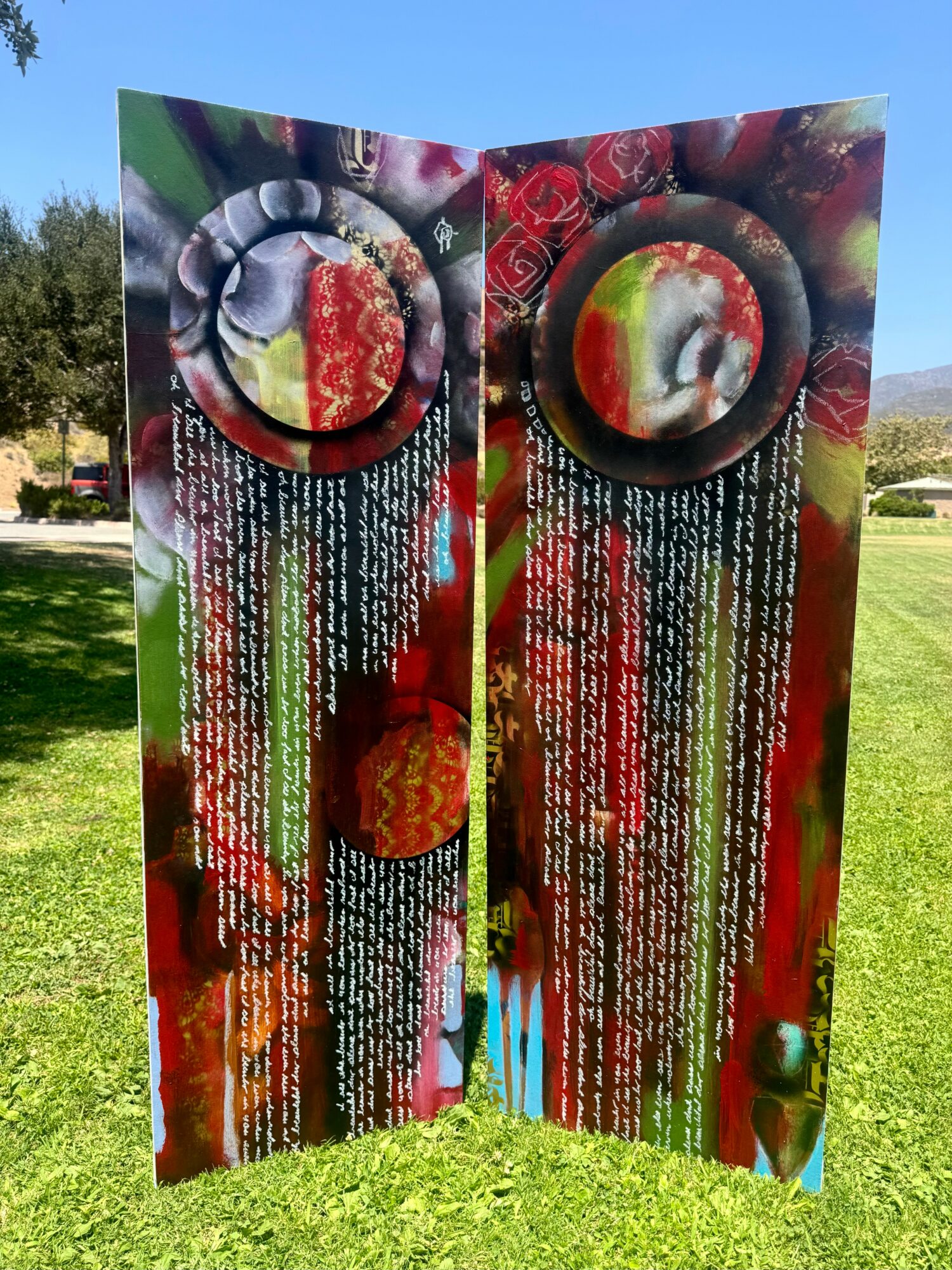 Two colorful vertical panels with circular designs at the top, containing text and images, outdoors on grass with trees in background.