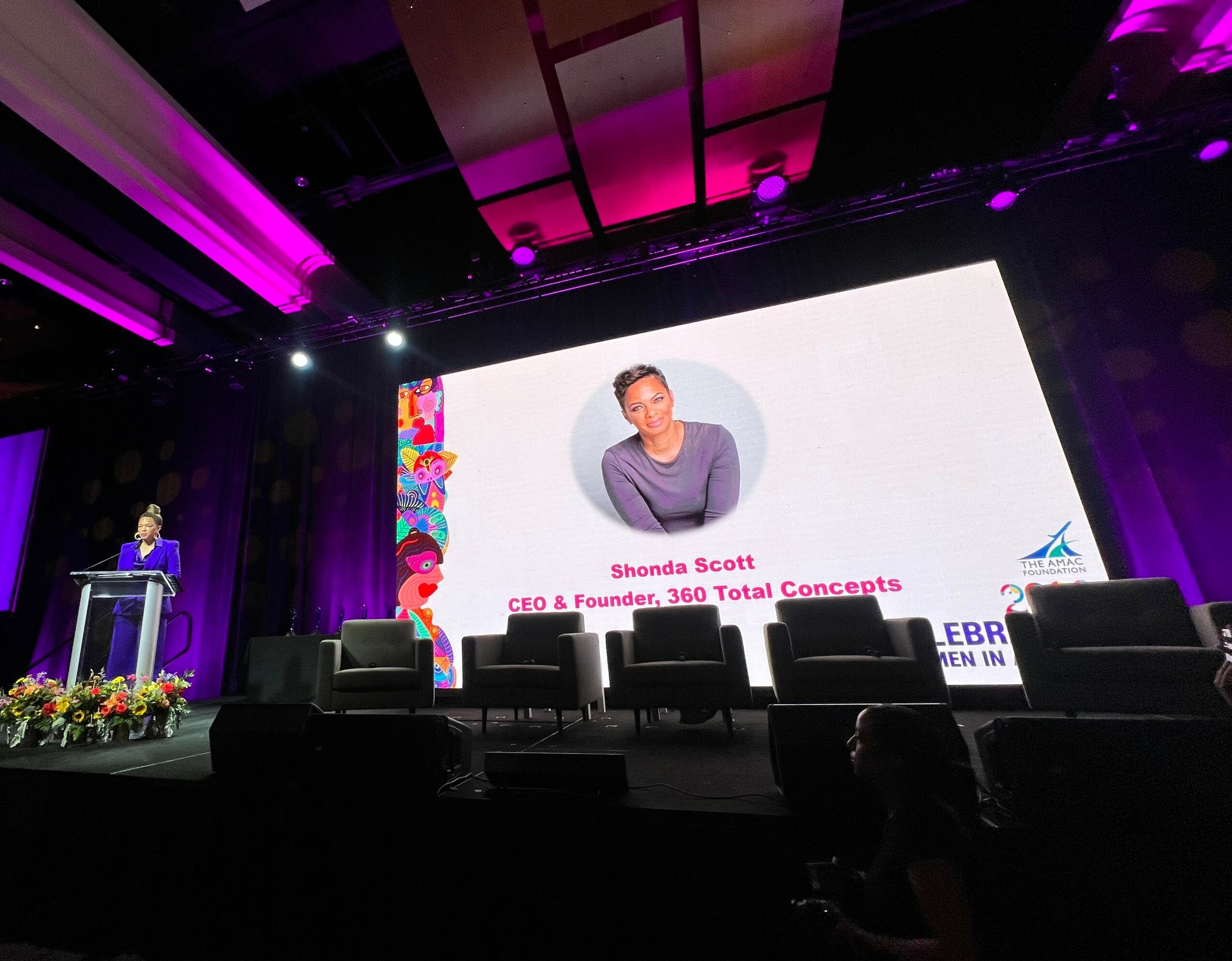 Large screen displays a woman with short hair, wearing a purple top, with text about Shonda Scott, CEO and founder.
