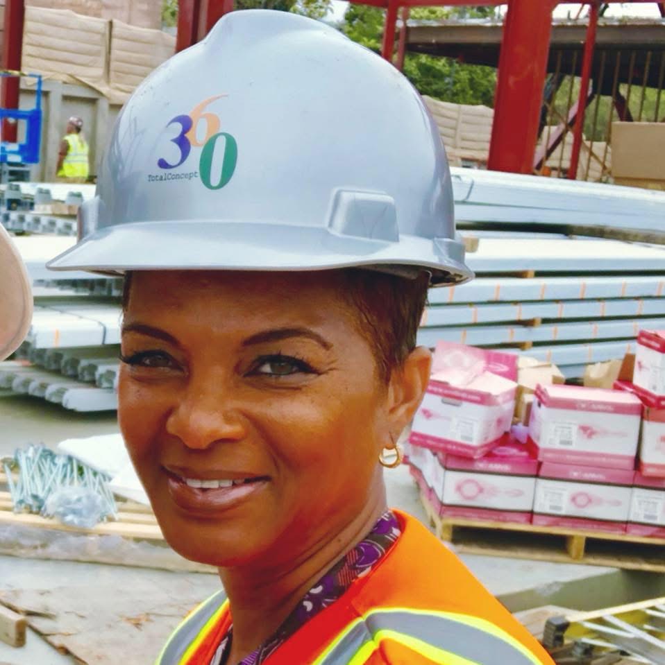 Woman wearing a white safety helmet with the number 30, smiling outdoors near construction materials.