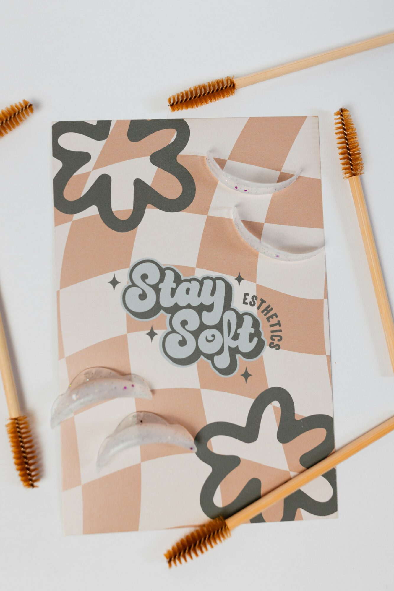 A flat lay of a skincare or cosmetic product brochure with brushes around it, featuring a checkered background and floral designs.