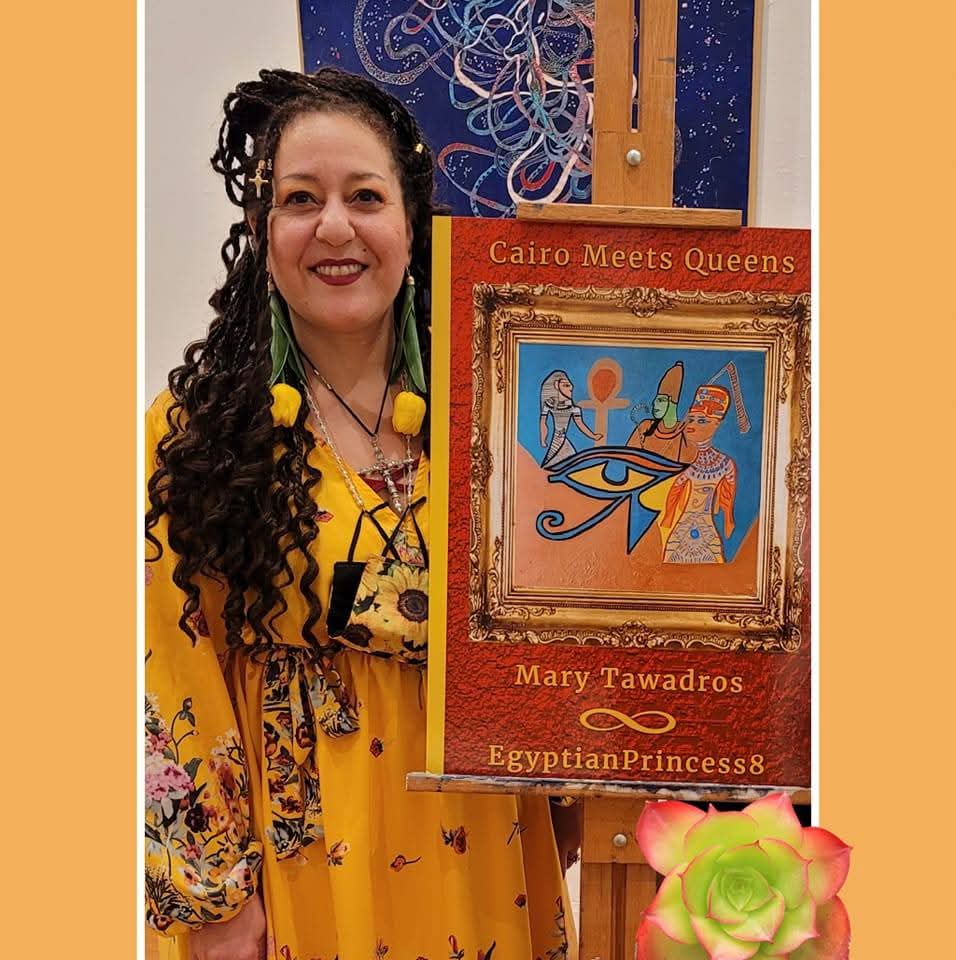 Woman with long curly hair wearing a yellow dress, standing next to a framed artwork titled 'Cairo Meets Queens'.
