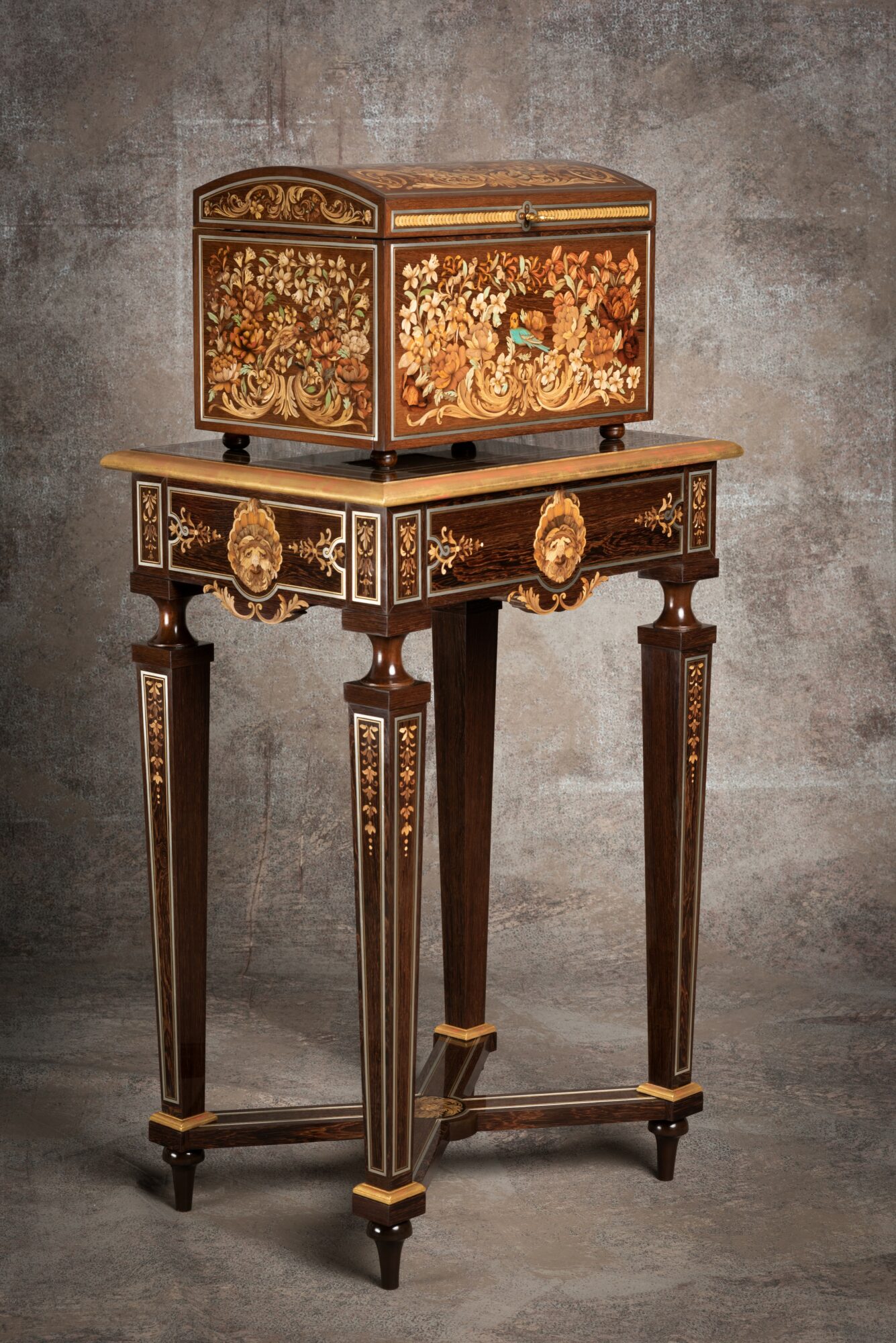 Decorative wooden table with a small ornate box on top, against a textured wall background.