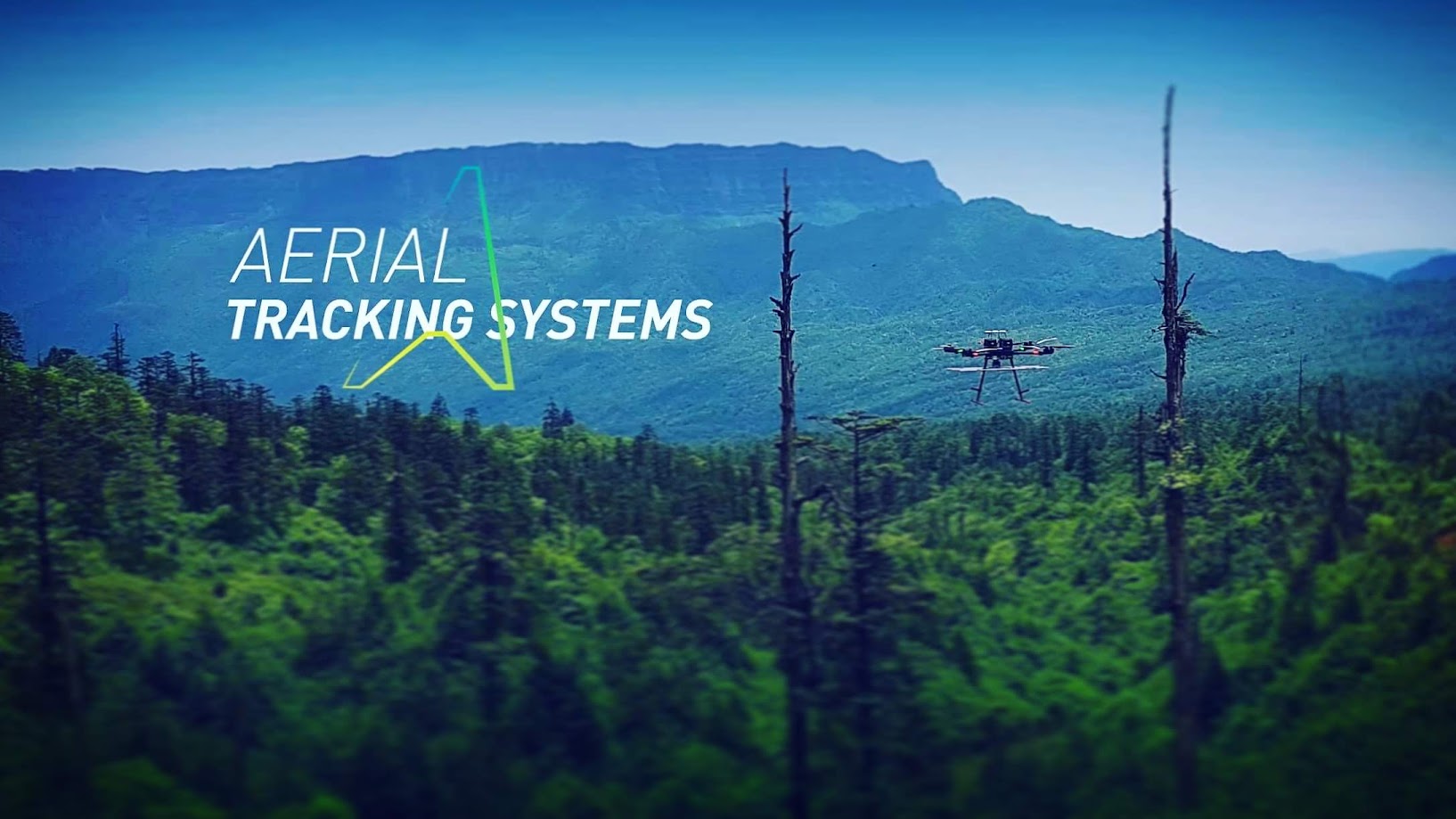 Drone flying over a green forest with mountains in the background, and text reading 'Aerial Tracking Systems'.