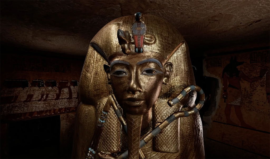 Ancient Egyptian sarcophagus with a gold face and headdress, decorated with jewelry and symbols, in a dimly lit tomb.
