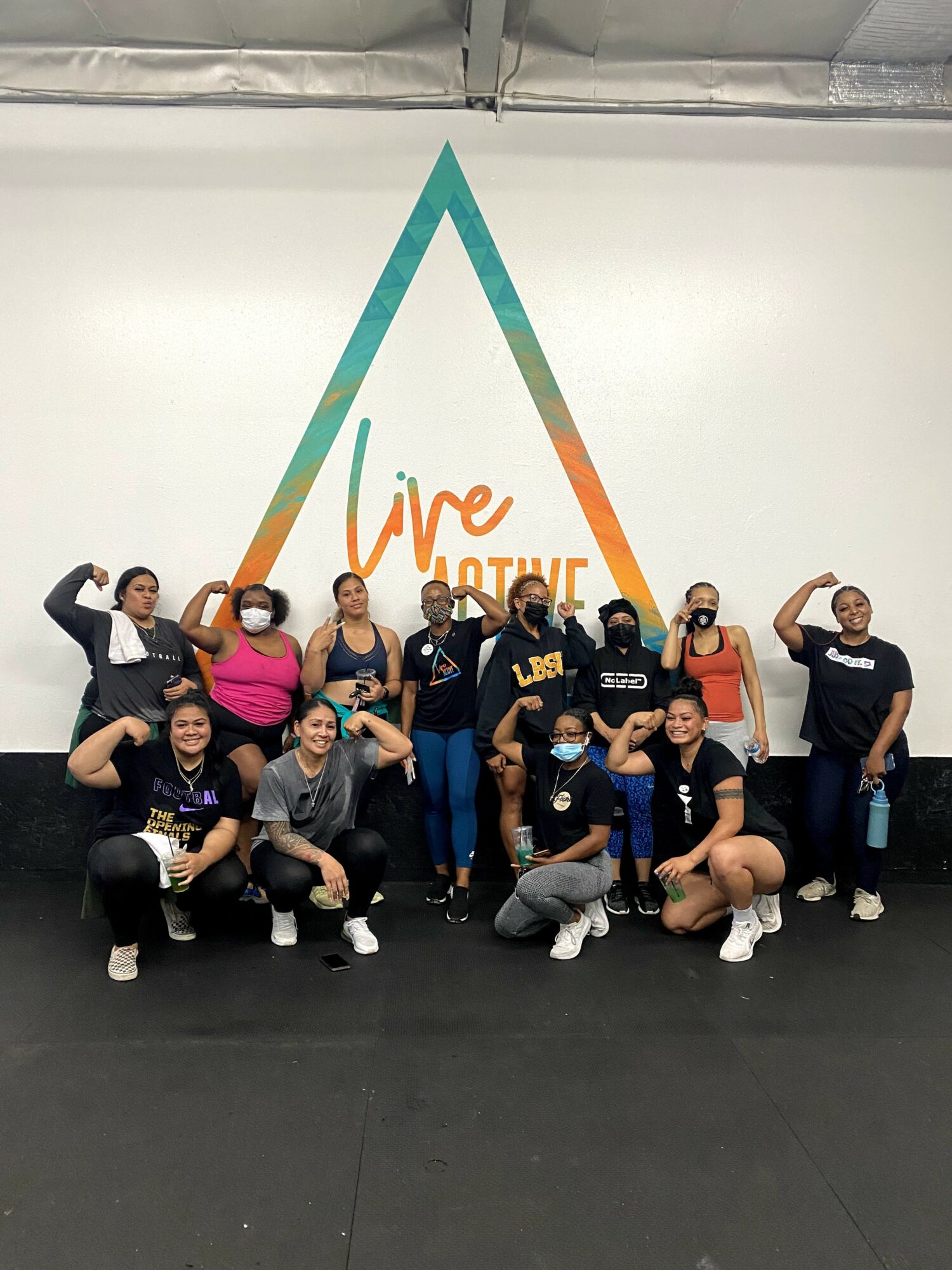 Group of people posing in front of a wall with a large triangle and the words 'Vive Juntas'.