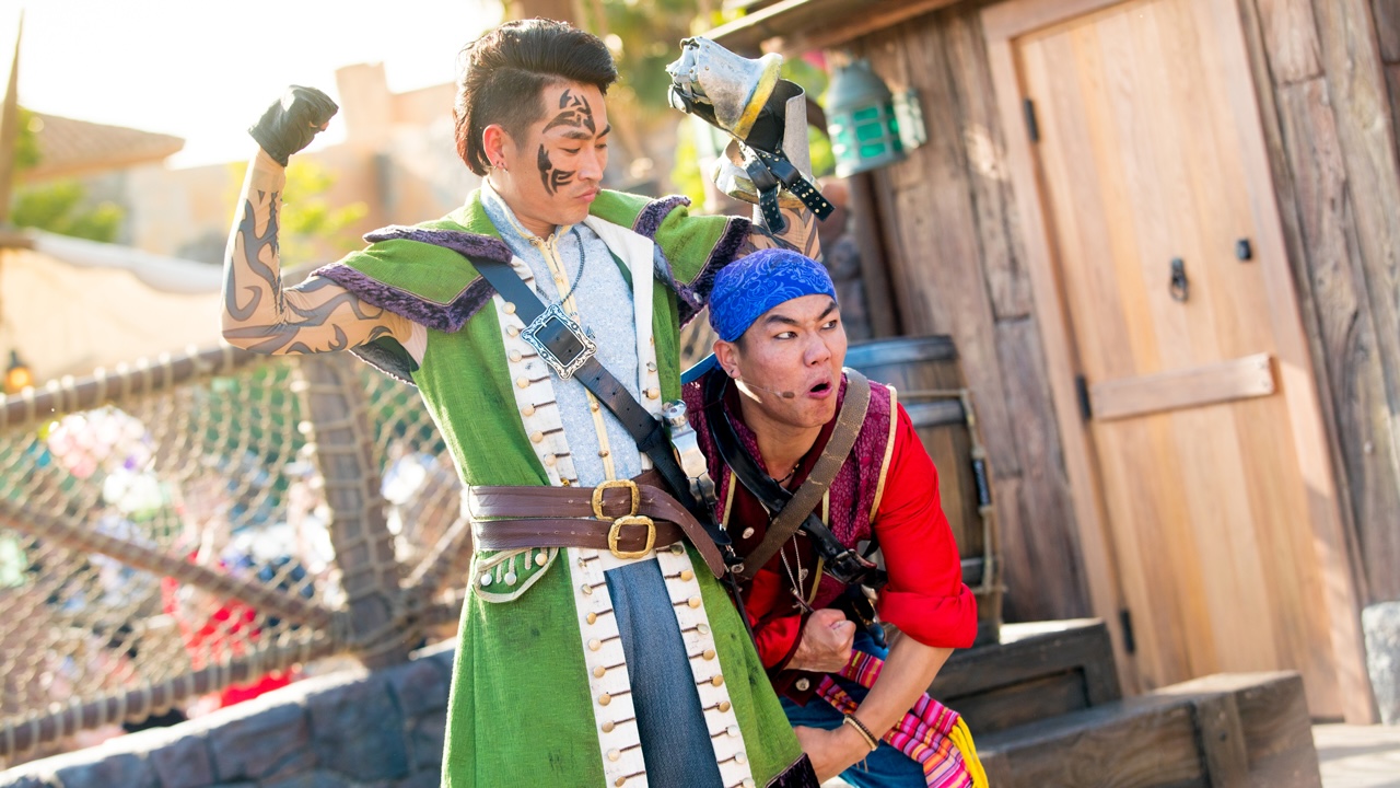 Two children in costumes, one in a green and blue outfit with face paint, the other in a red and blue costume, outdoors.