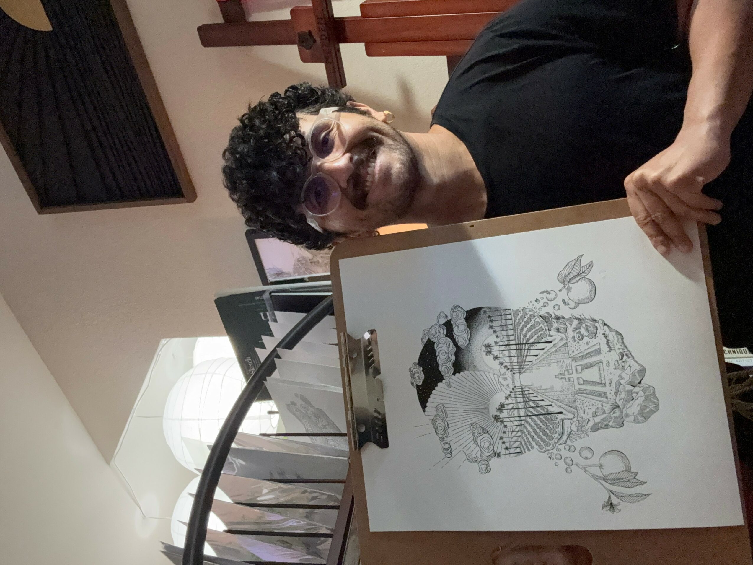 Person with curly hair and glasses holding a detailed black-and-white drawing of a person in traditional attire.