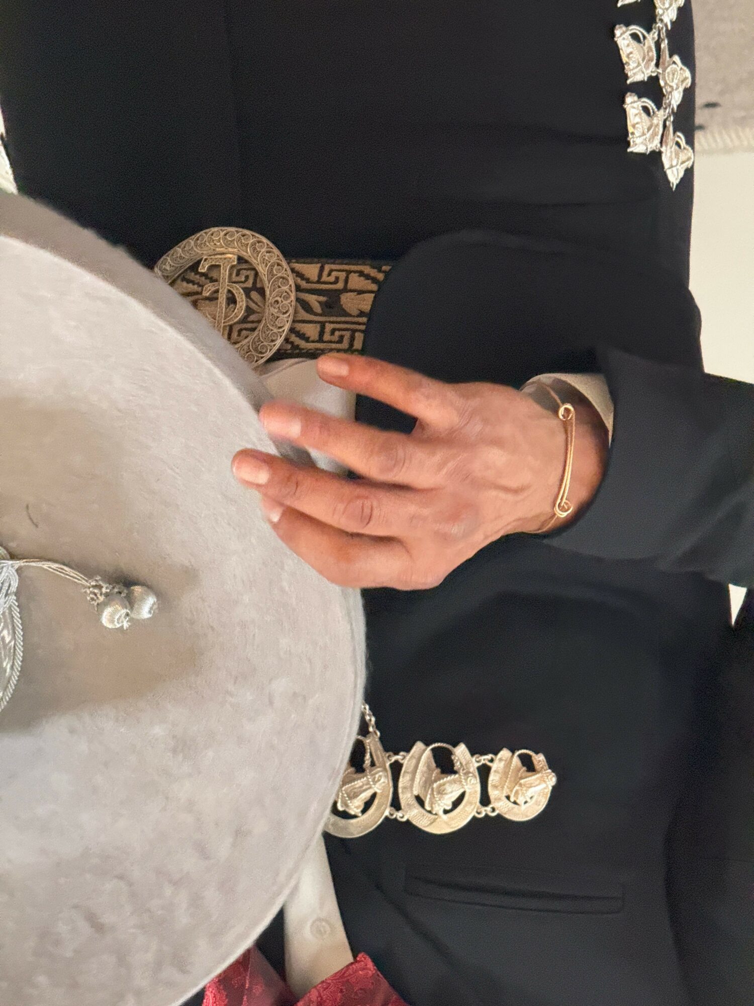 Person holding a large round object, wearing a black outfit with decorative elements, and a bracelet on their wrist.