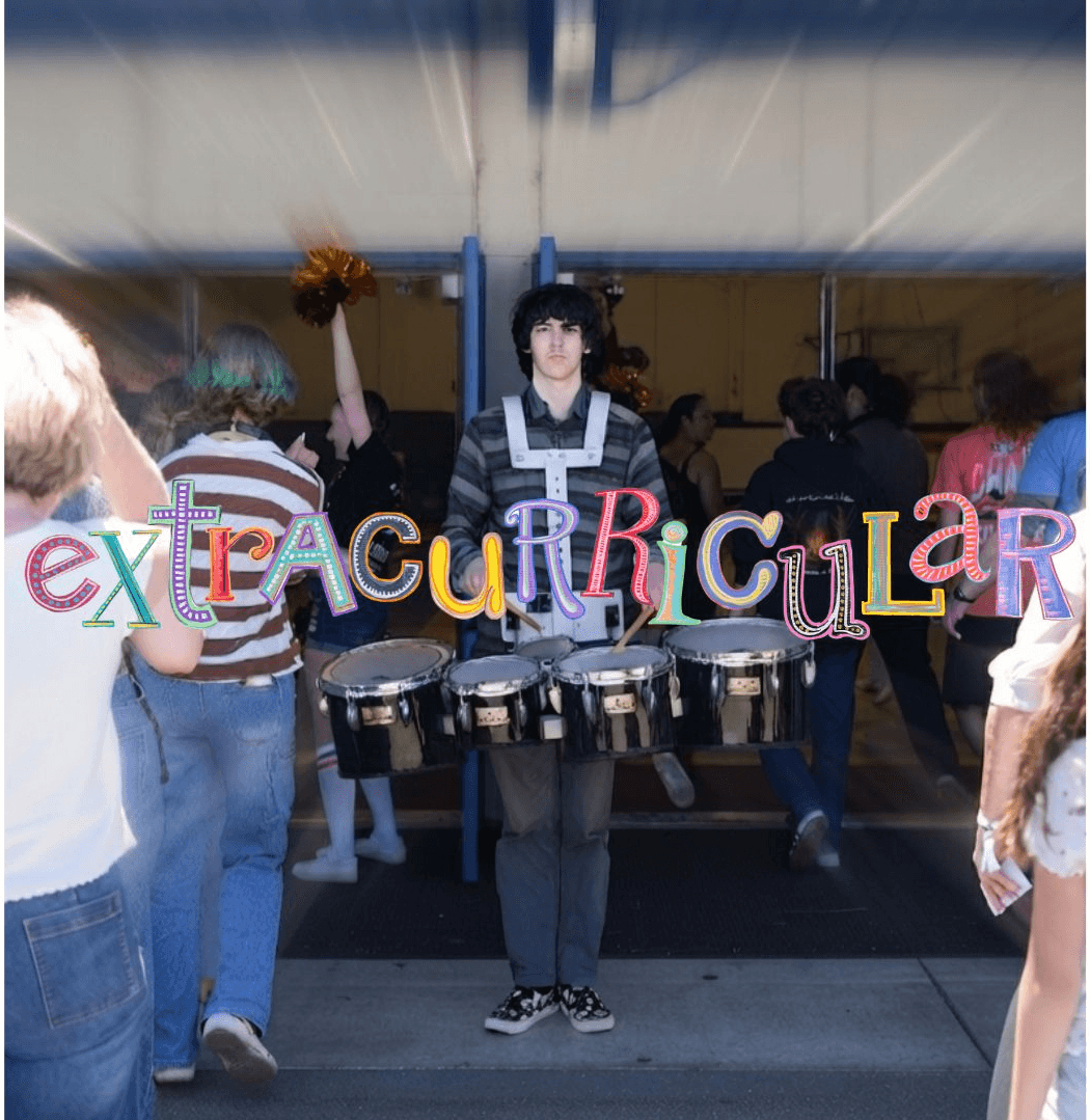 Person playing drums behind a colorful sign spelling 'extraordinary' at an indoor event.
