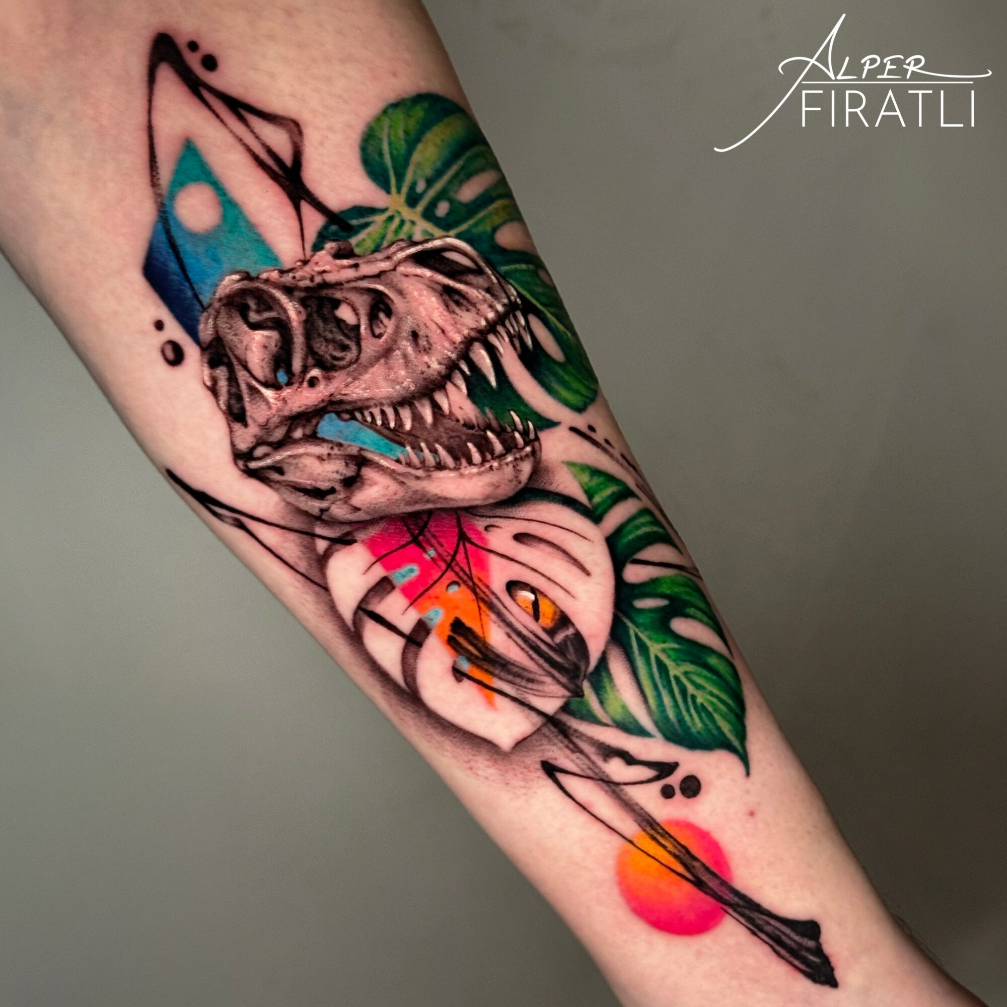 Tattoo of a dinosaur skull with colorful geometric shapes and green leaves on a person's arm.