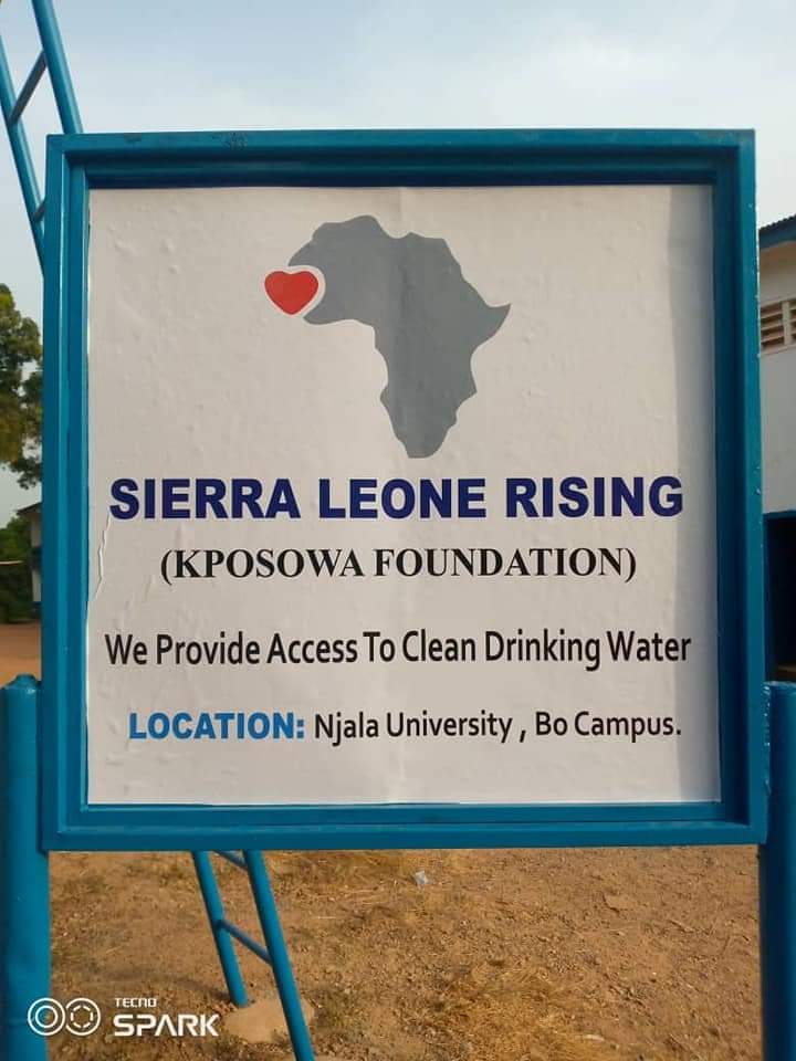 Sign with Africa map, red heart, and text about Sierra Leone Rising and water access at Njala University.