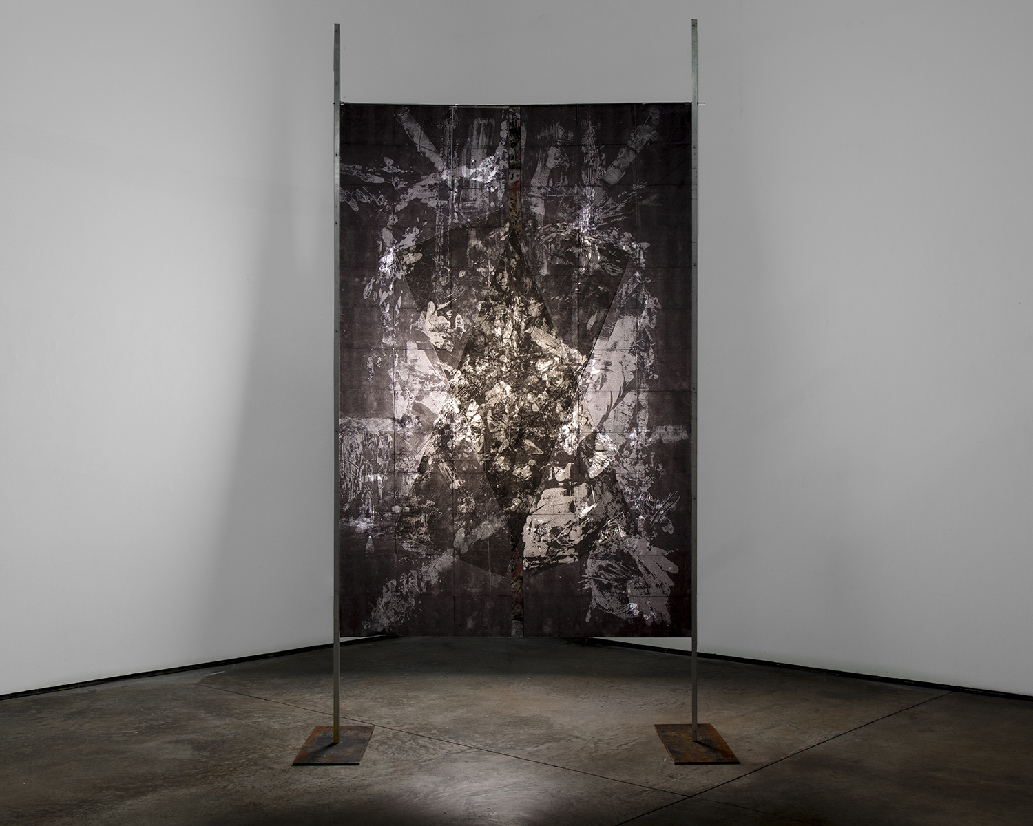 Artwork displayed on a freestanding panel in a gallery, with a dark, abstract design and light reflections.