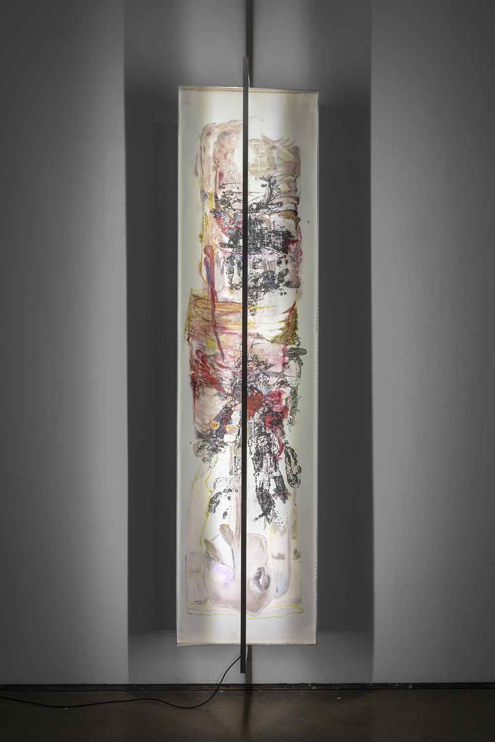 Vertical abstract artwork with various colors and textures, illuminated and mounted on a wall, with a black vertical line in the center.