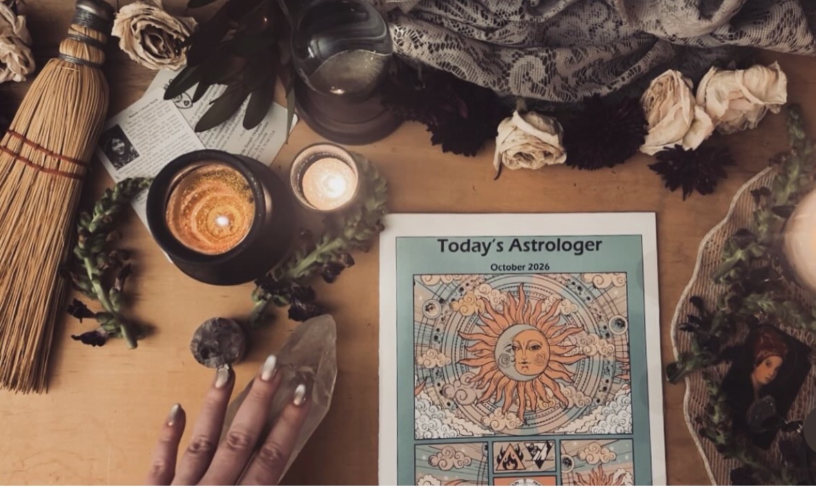 Astrology chart titled 'Today's Astrologer' on a table with candles, crystals, and decorative items.