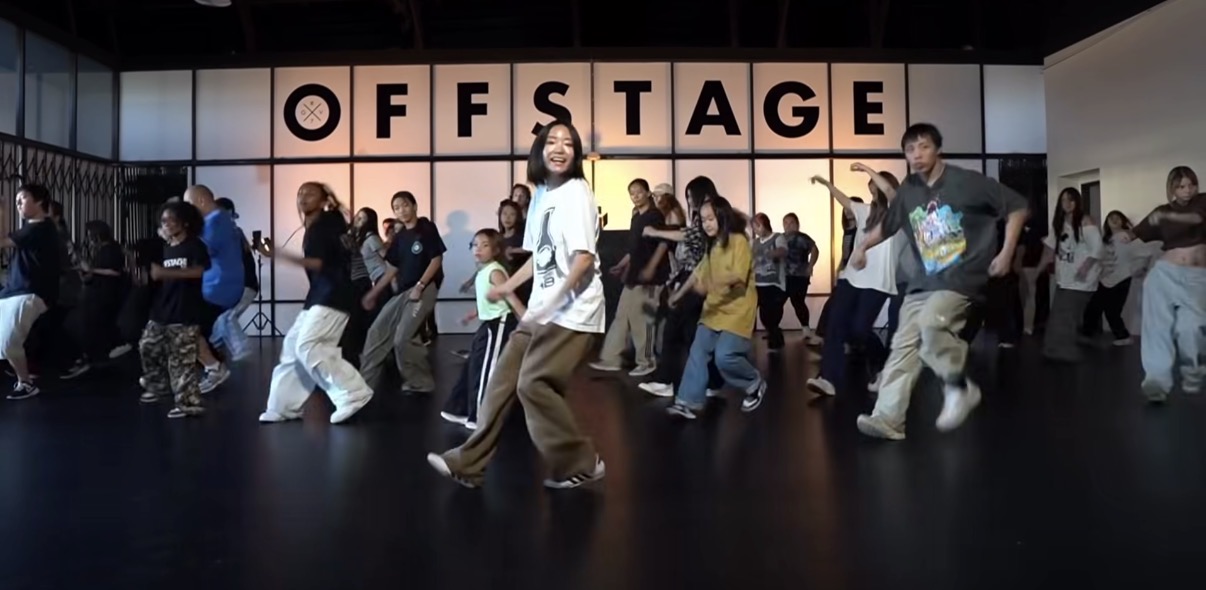 Group of people dancing in front of a sign that reads 'OFF STAGE'.
