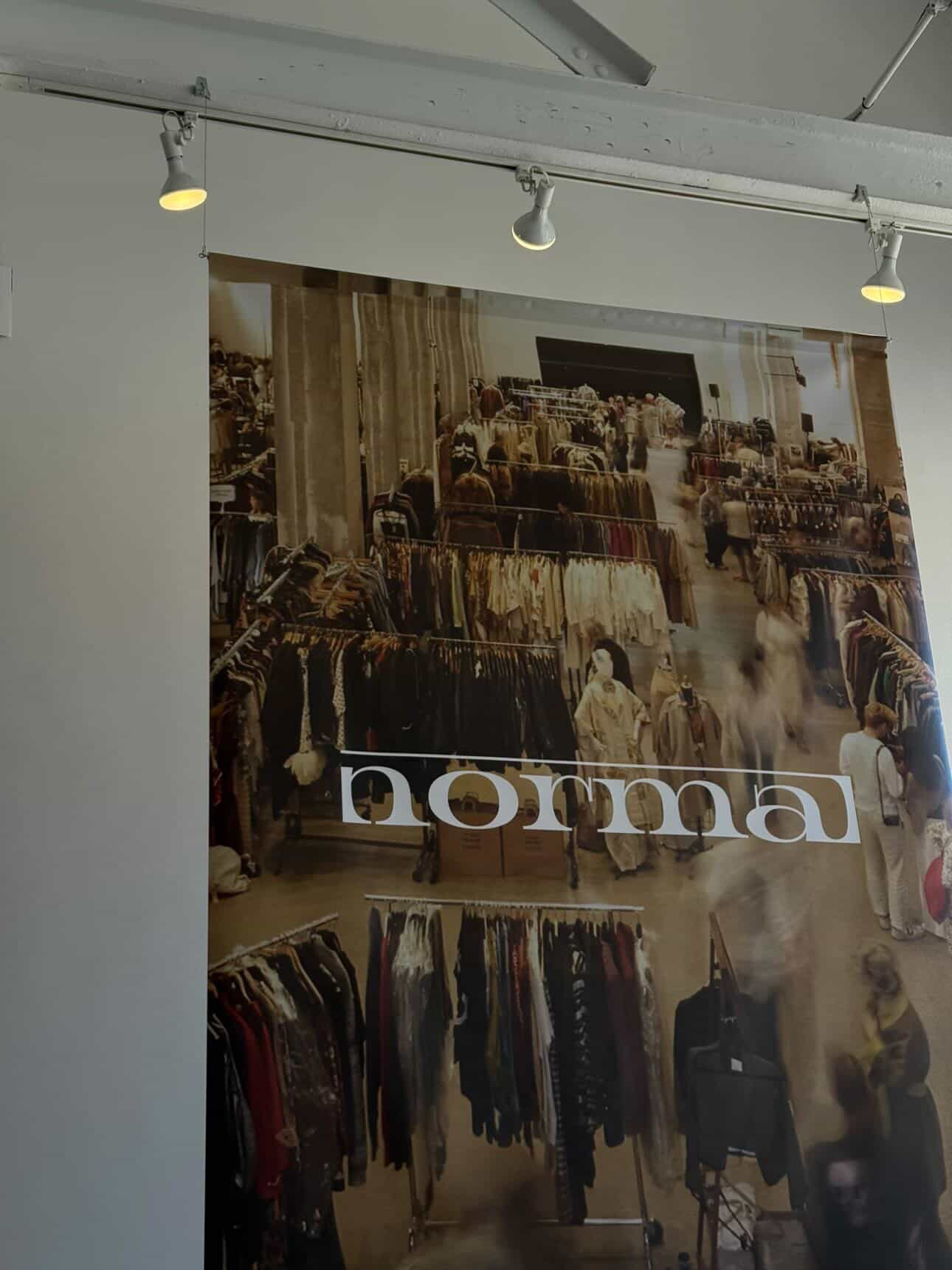 Clothing store interior with racks of clothes and a sign reading 'normal'.