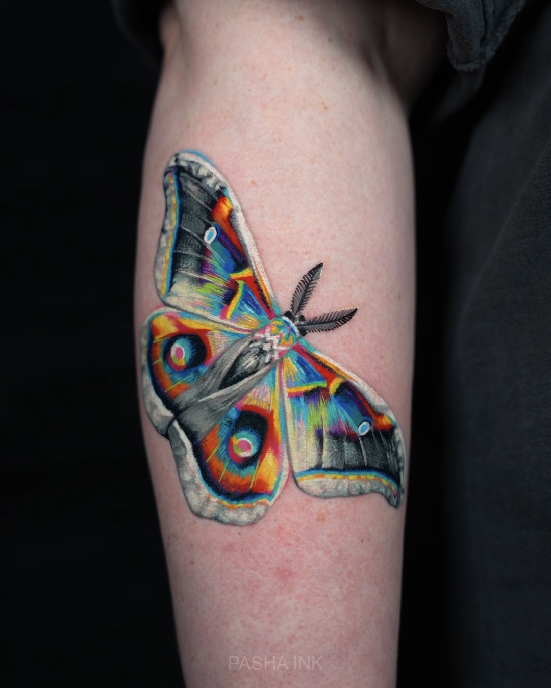 Colorful butterfly tattoo on person's arm with detailed wings and vibrant colors.