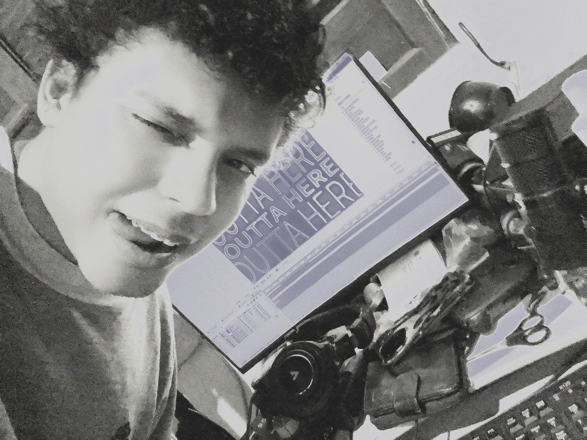 Young person with curly hair in front of a computer monitor displaying a graph, in black and white.