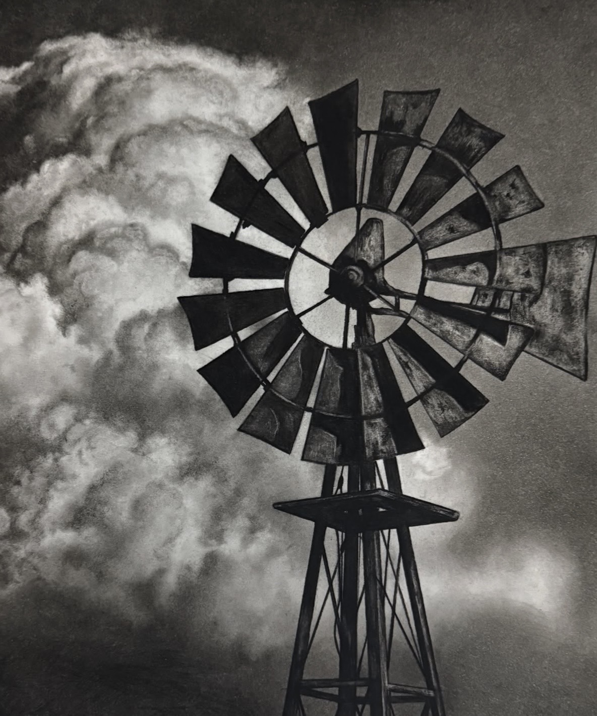 Windmill with broken blades against cloudy sky, black and white image, tall structure, large clouds, dramatic scene
