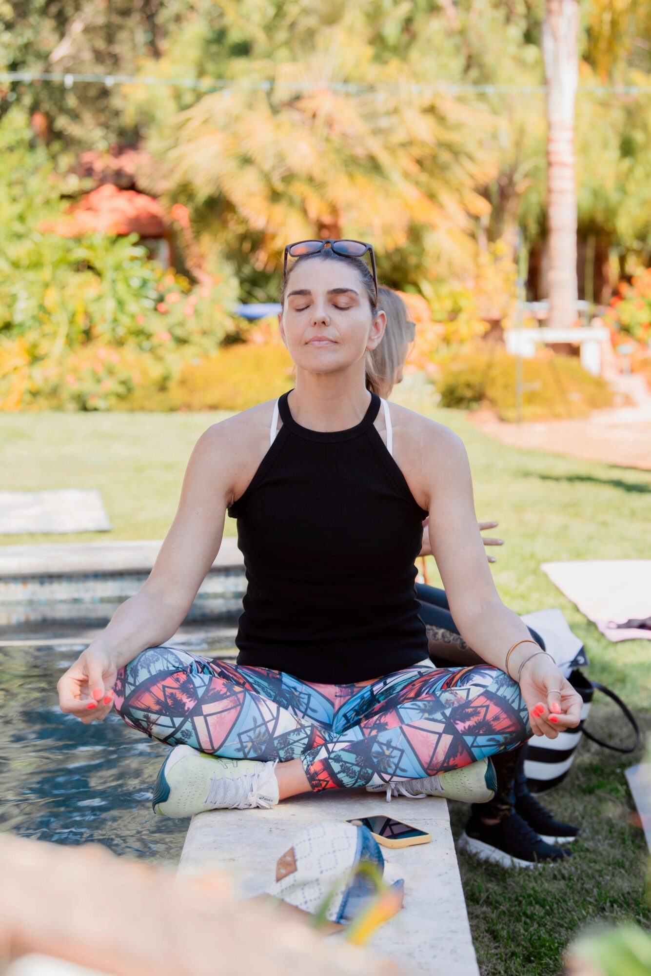 Woman meditating outdoors on a bench with trees and autumn foliage in background.