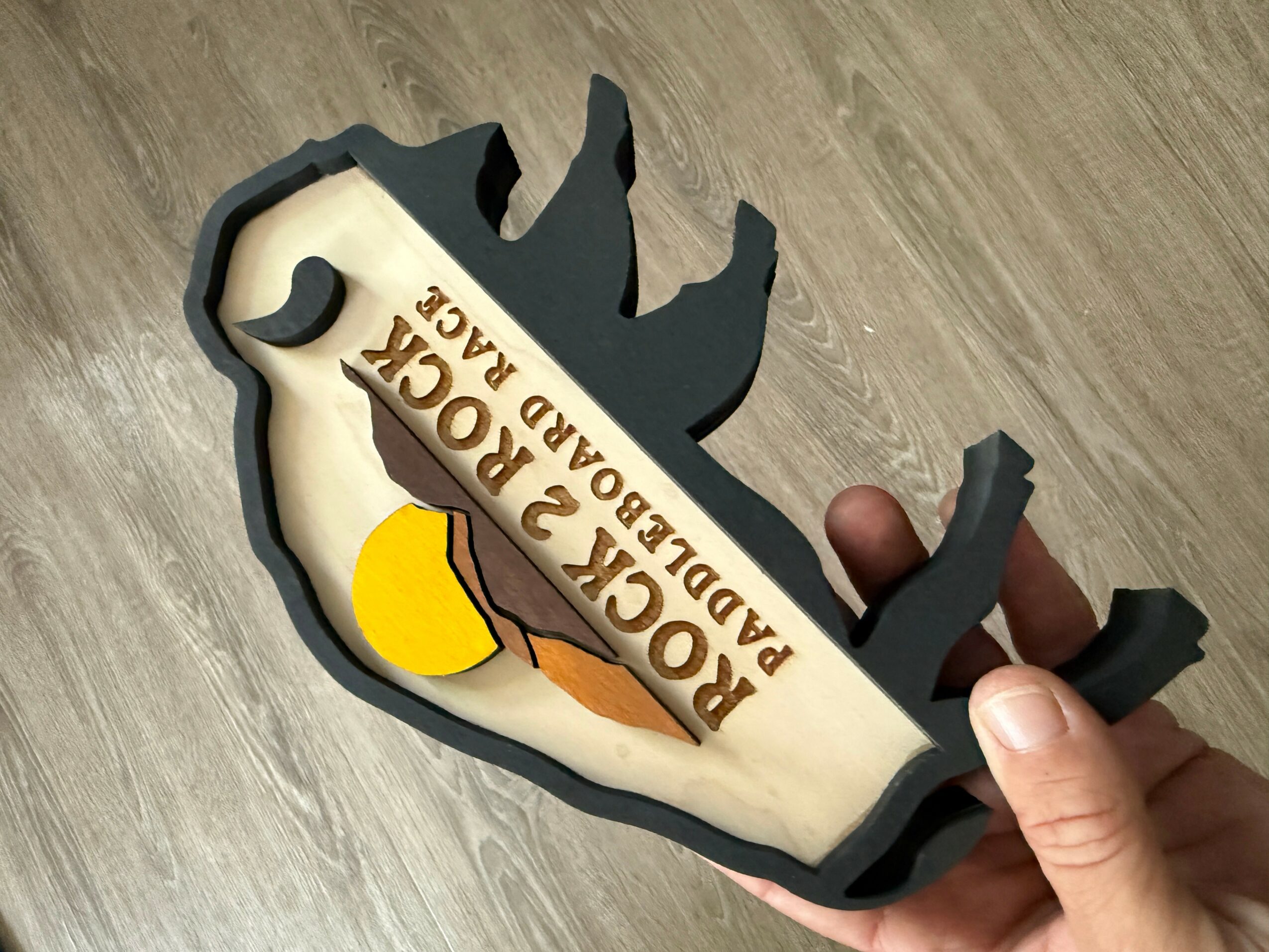 Hand holding a duck-shaped cake mold with a cake inside, decorated with a sign reading