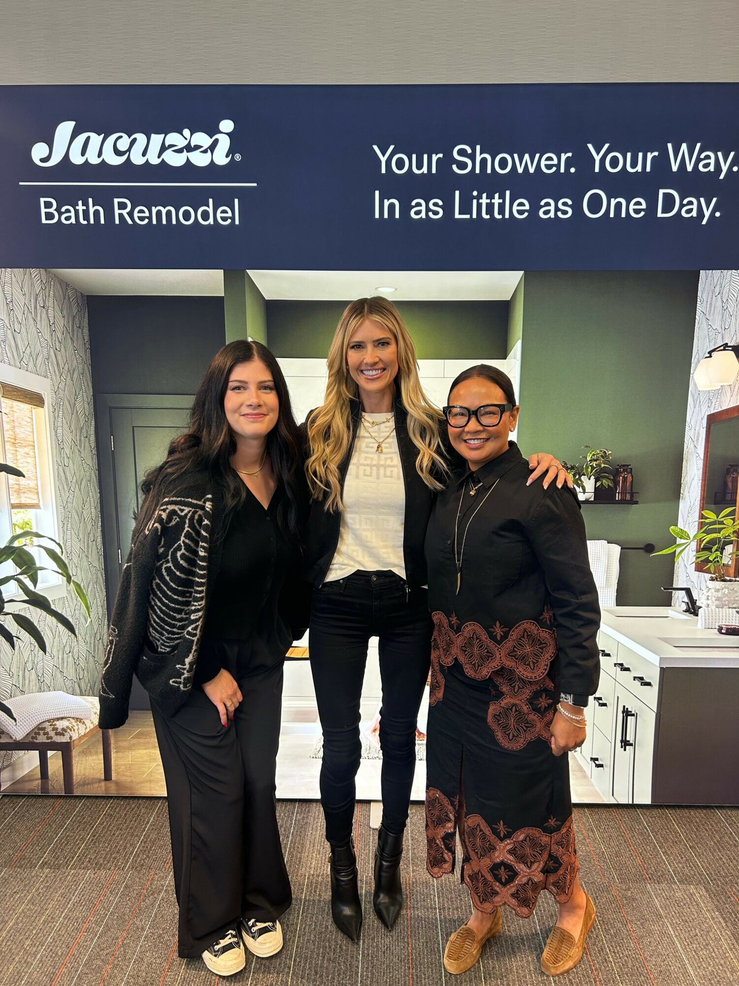 Three women standing together in a room with a sign that reads