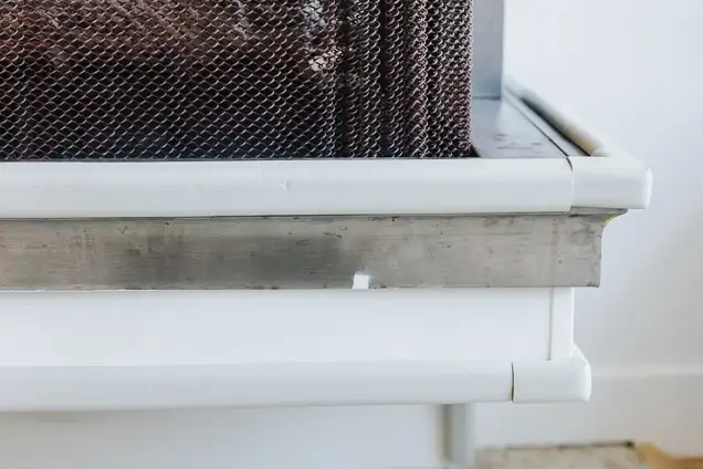 Close-up of a white window frame with a mesh screen and a concrete ledge, viewed from below.
