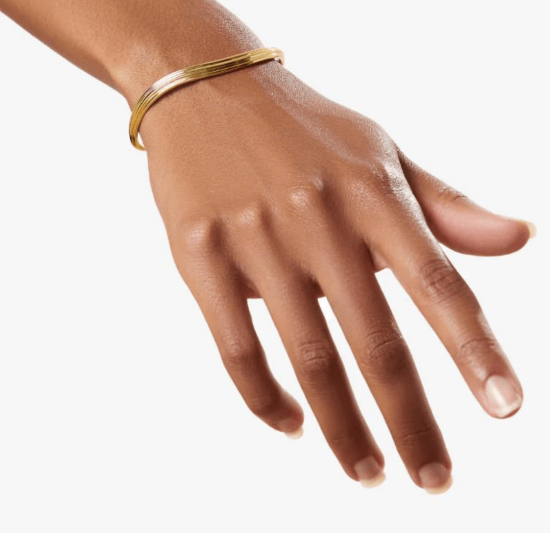 Hand with a gold bracelet, fingers extended, palm facing downward, neutral background.