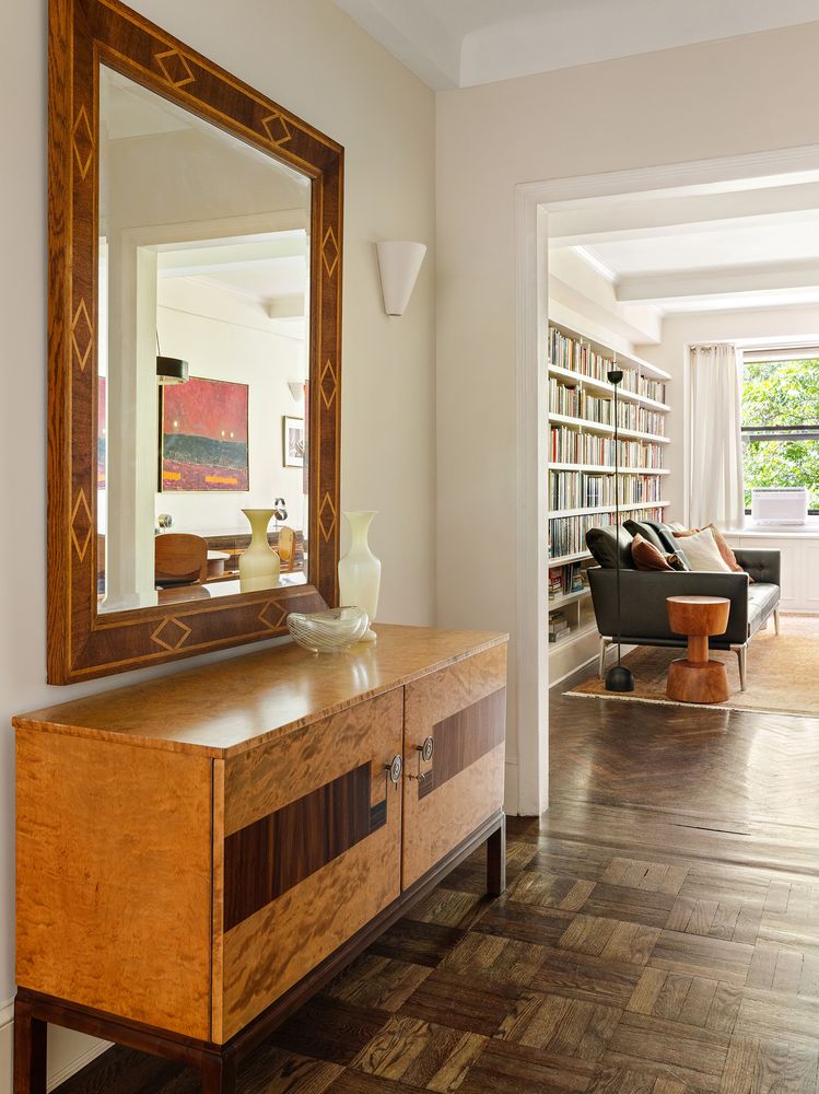 Wooden sideboard with a large mirror above, in a room with light-colored walls and hardwood floor.