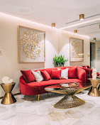 Living room with red sofa, gold side tables, and wall art, illuminated by ceiling lights and ambient lighting.